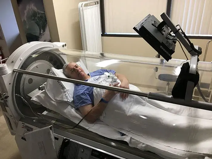 Patient Joe Cabral lying in medical chamber while receiving hyperbaric oxygen therapy.