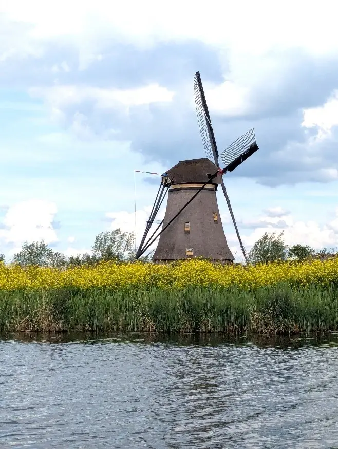 A windmill in front of a river.