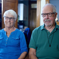 Bernie and Marita Hart smile while sitting together in their living room.