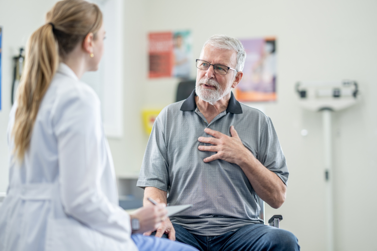 A senior man talking with a physician in an examination room.