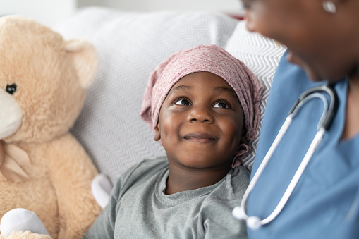 A child smiles while looking up at a pediatric emergency room nurse.