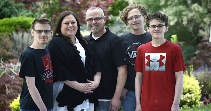 Jeni Limb is surrounded by their family in an outdoor setting.