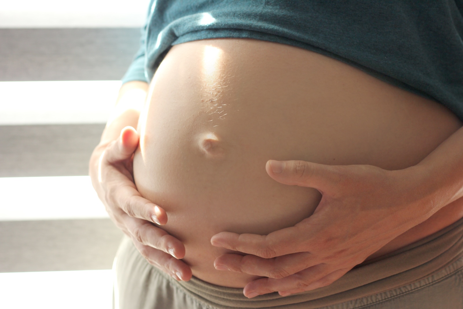 A pregnant woman with her hands on her belly.