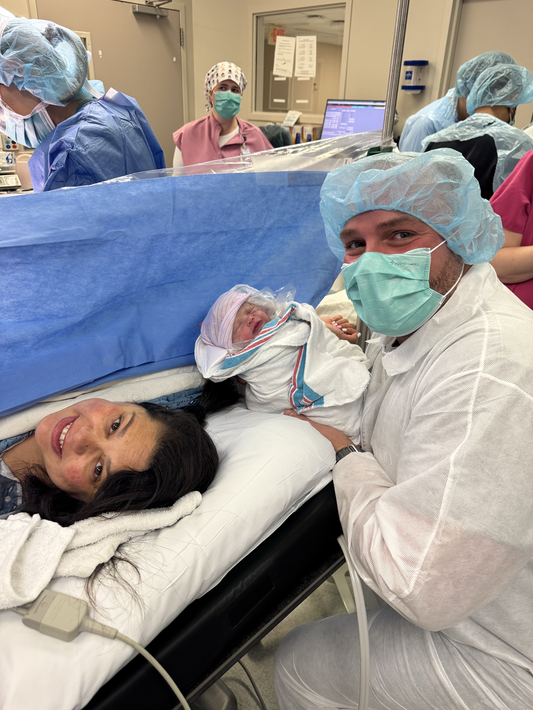 April after giving delivery in the hospital room while the doctor holds the baby.