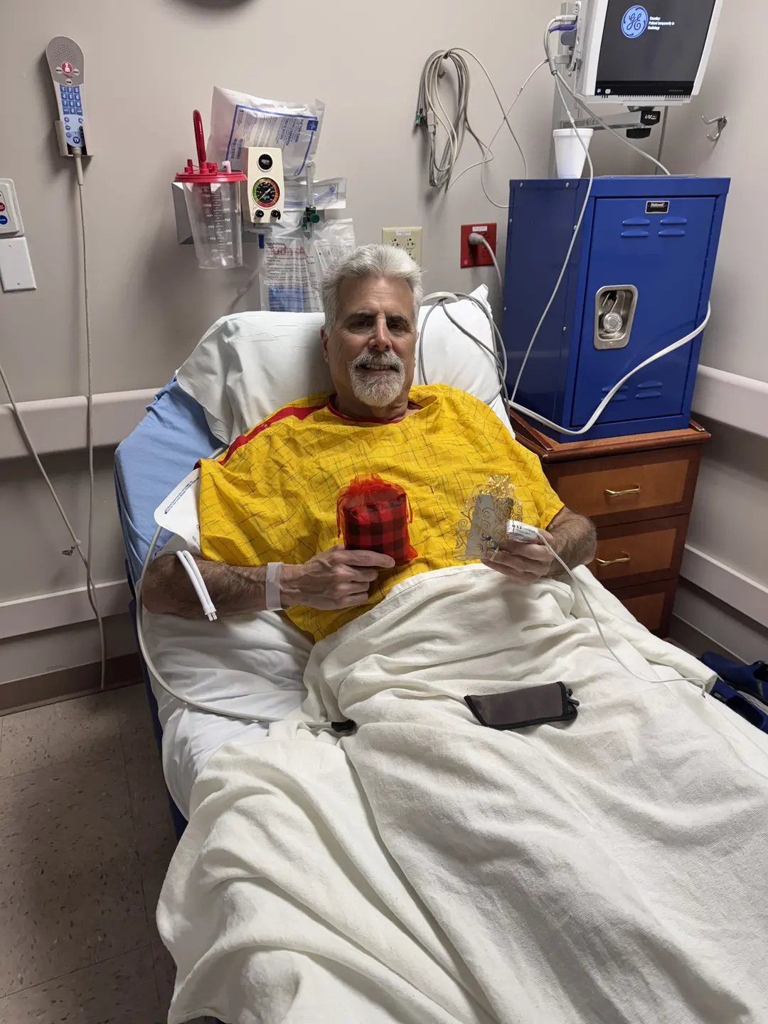 Male patient in his bed, holding the handmade pillow and smiling.