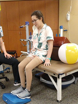 Marissa Little is seated working out in rehabilitation