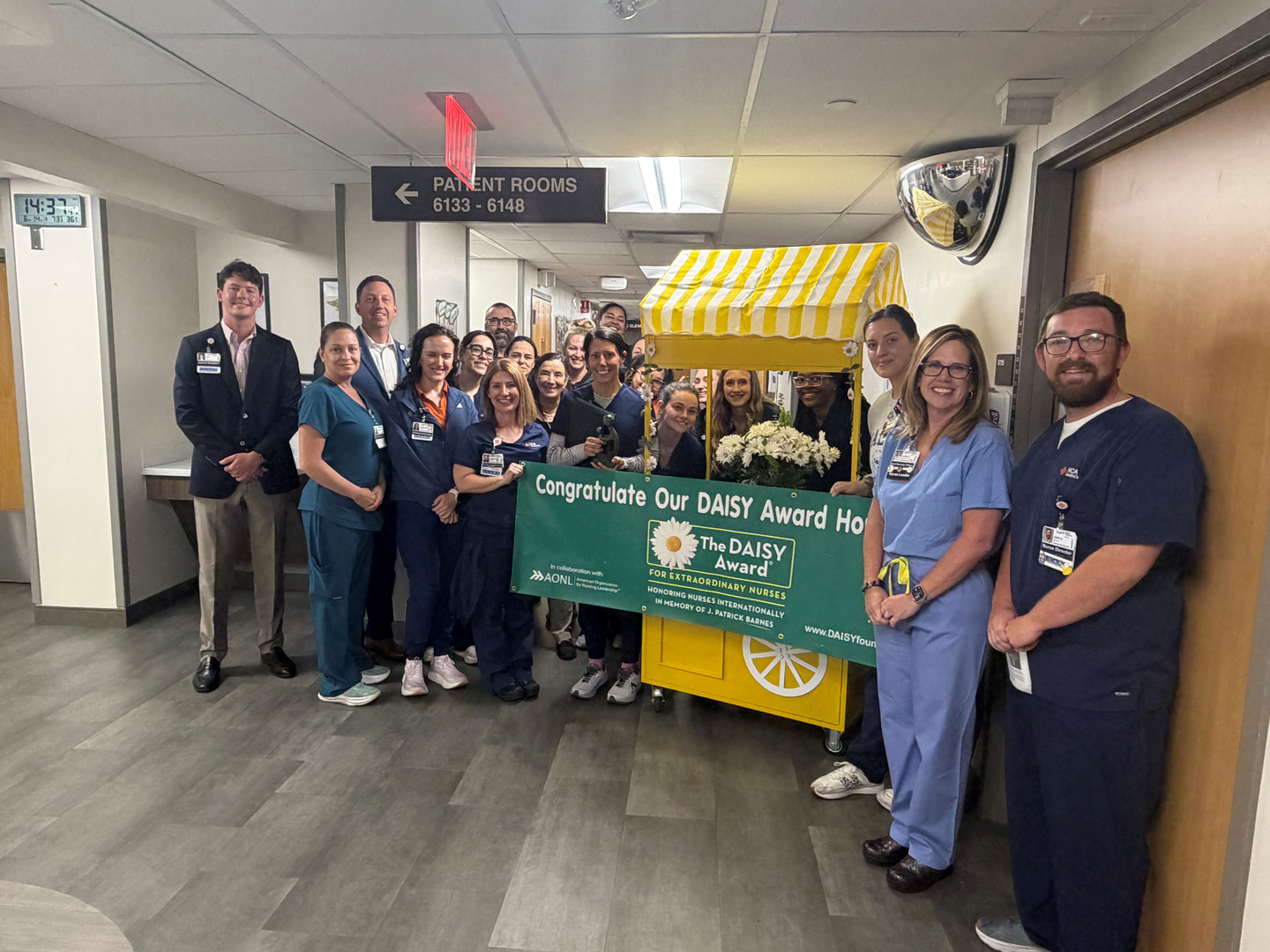 Justine Cox and her team smiling and posing for a photo, while holding the daisy award banner.