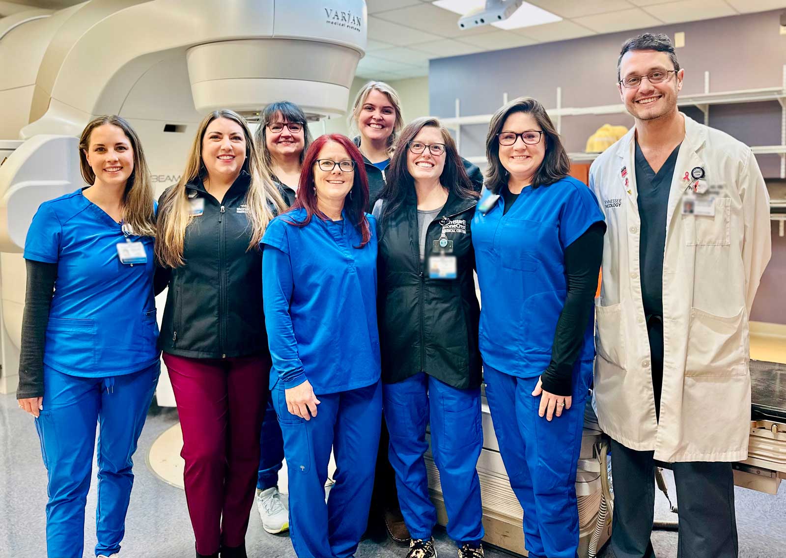 A group photo of the TriStar StoneCrest Medical Center radiation oncology team, including physicians, nurses, and staff, standing together in front of advanced medical equipment. The team is smiling, reflecting their dedication to providing exceptional cancer care.