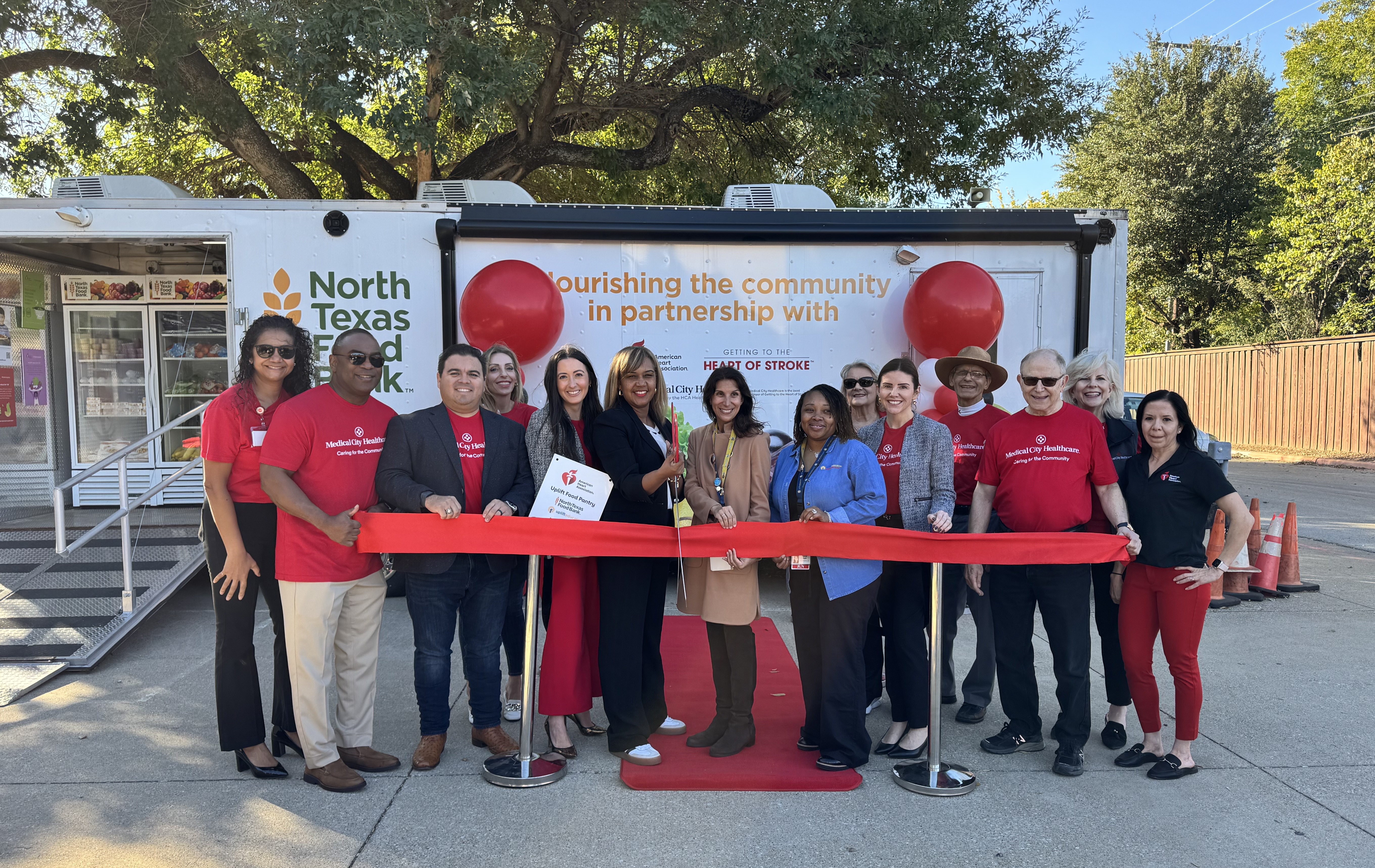 Group gathered in front of the food pantry, with a red ribbon