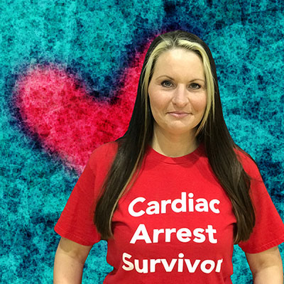Teri Edelson smiling and wearing a t-shirt that reads: Cardiac Arrest Survivor.