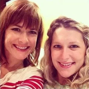 Two females are standing together, smiling at the camera