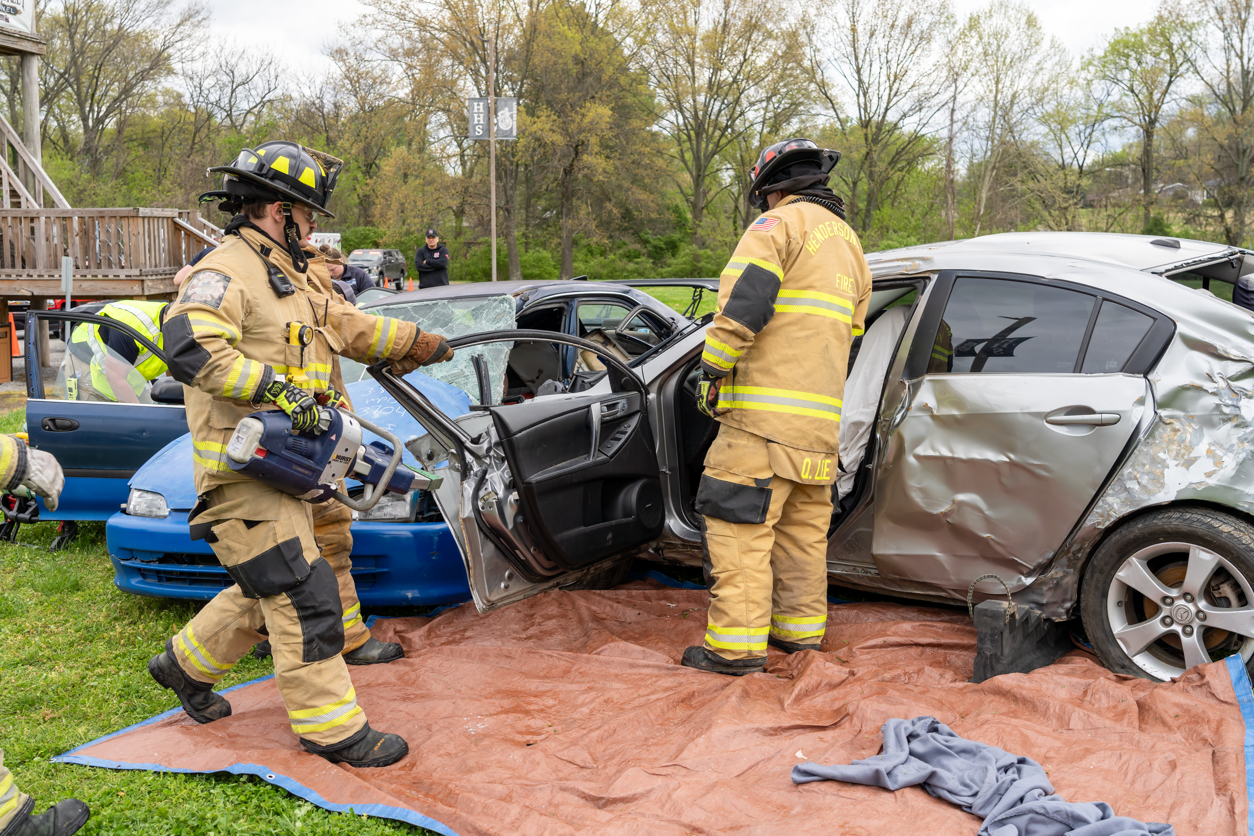 Two emergency personnel extracting victims from two crashed vehicles in the mock crash simulation.