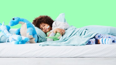 A sick child in bed with a thermometer in their mouth and stuffed animals around.