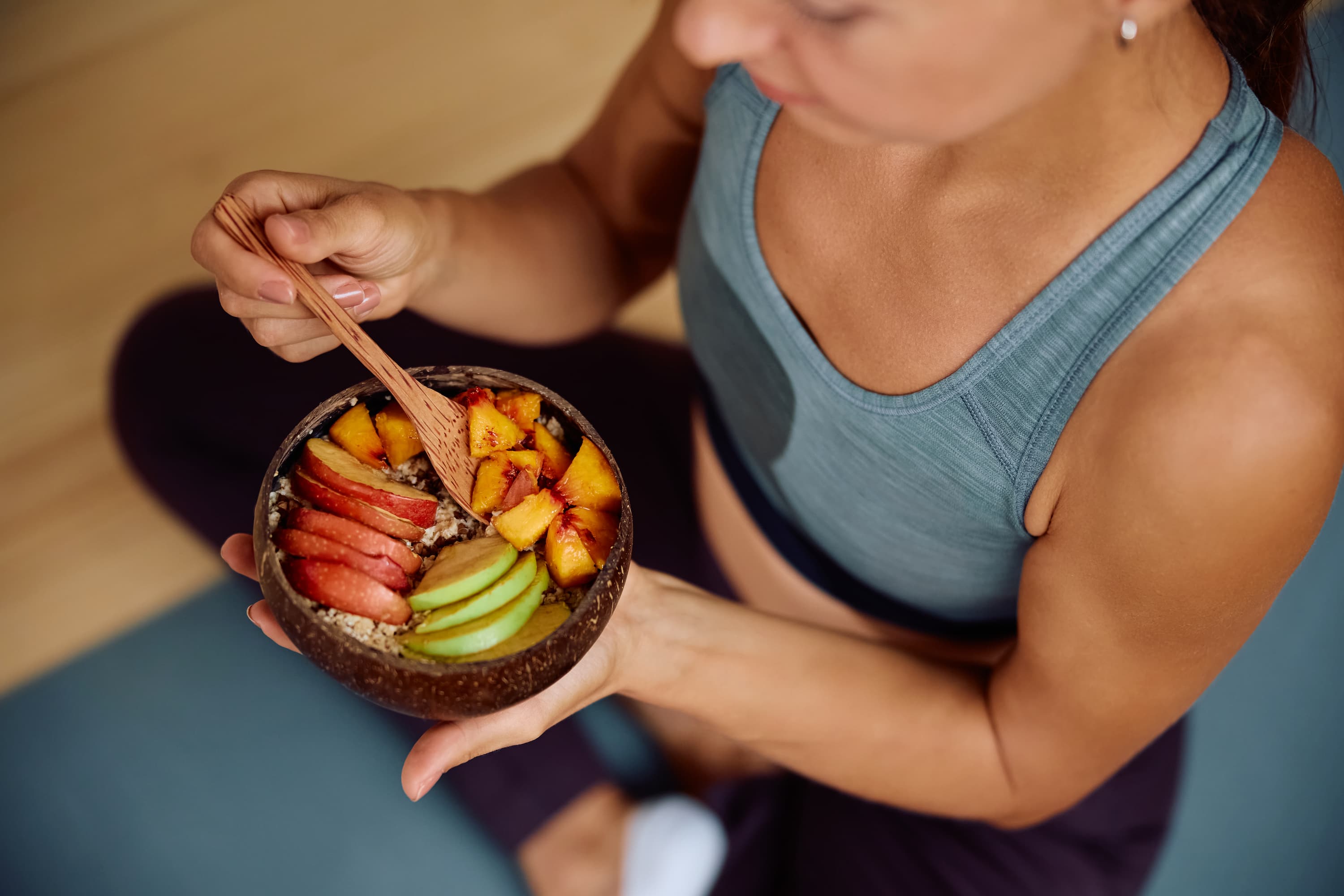 A woman eating a bowl of fruits and vegetables.