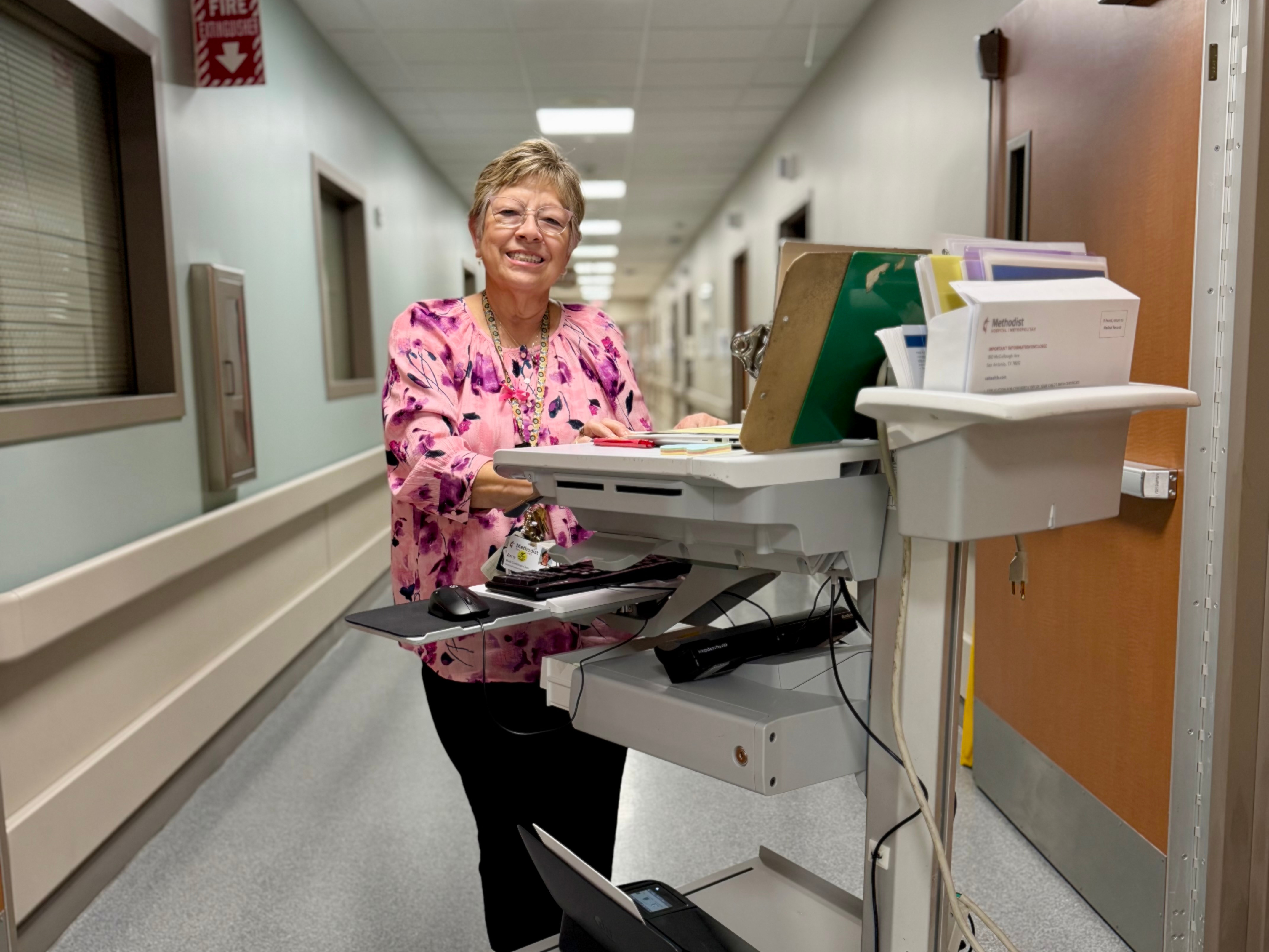 Betty Nuñez smiles while standing behind a desk with baked goods in an office.