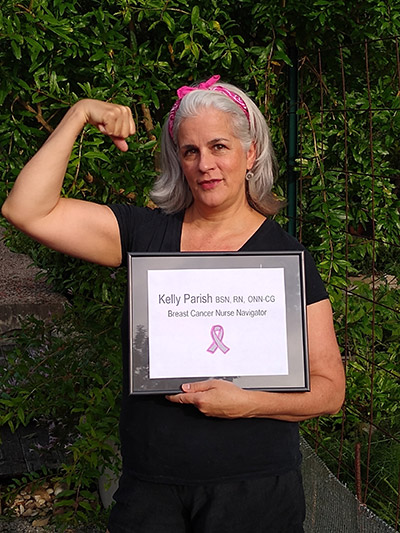 Nurse Kelly Parish holding a framed picture that says "Kelly Parrish BSN RN ONN-CG Breast Cancer NUrse Navigator".