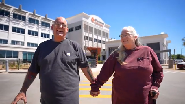 Lora Musikantow and husband holding hands walking outside of the hospital