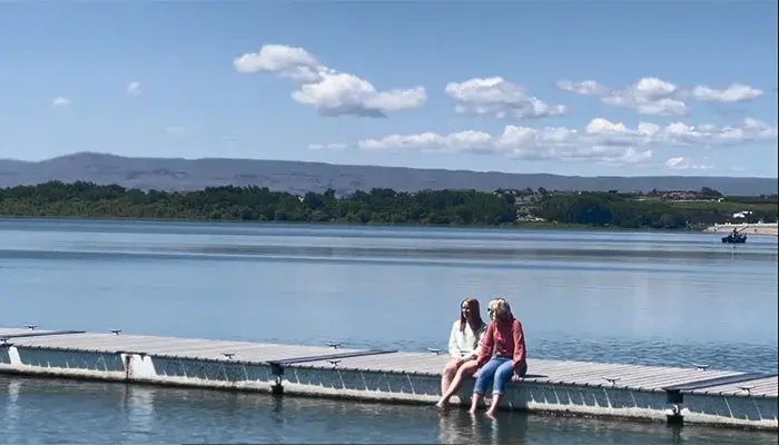 Caldwell resident Hanna and family member sitting on a dock by a body of water.