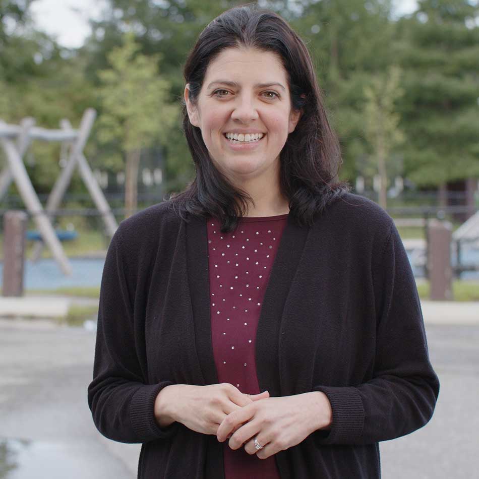 Chelsea Hunt standing outside a playground, smiling at the camera.