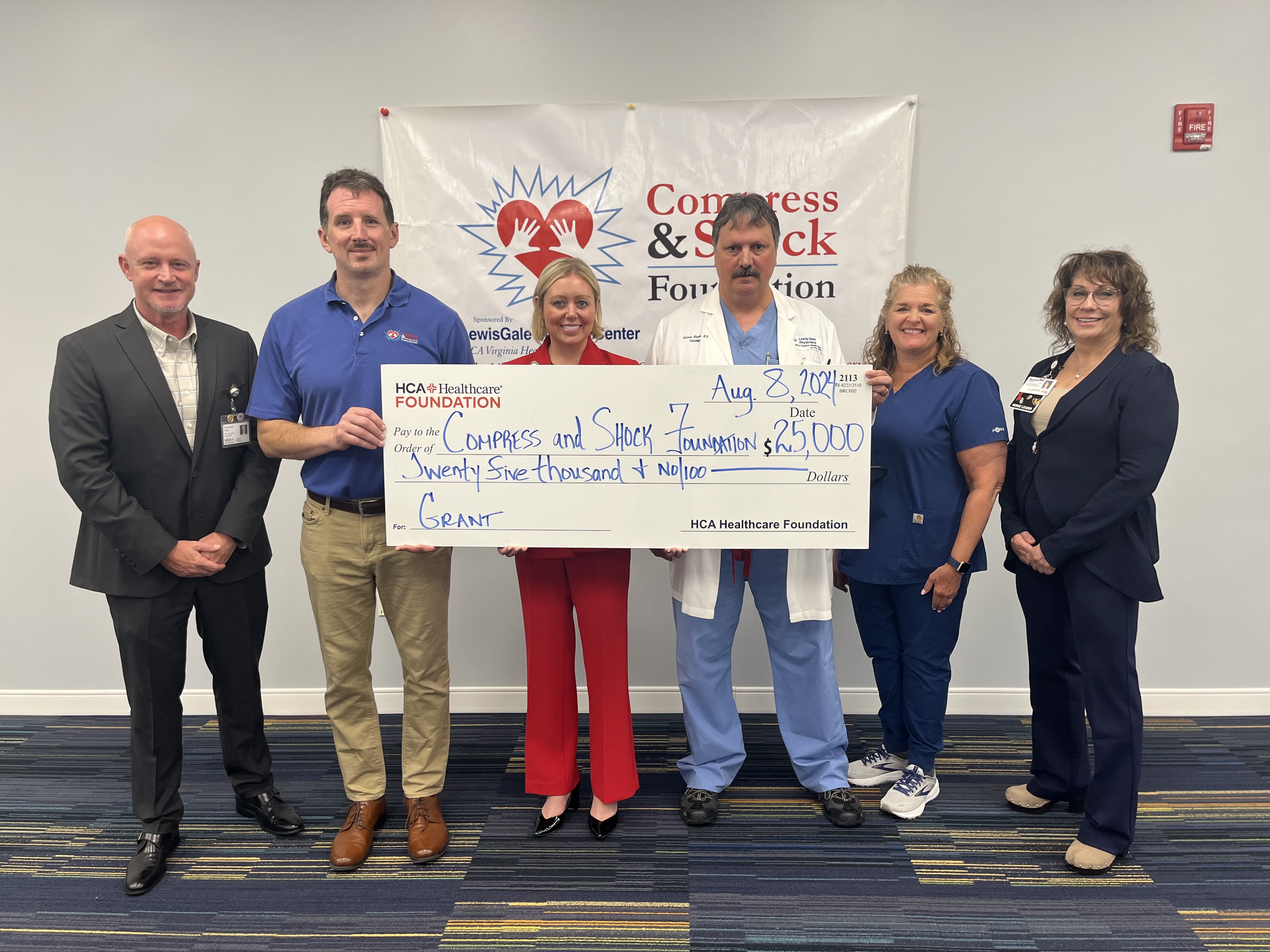 HCA staff presents $25k giant novelty check to members of the Compress and Shock Foundation.