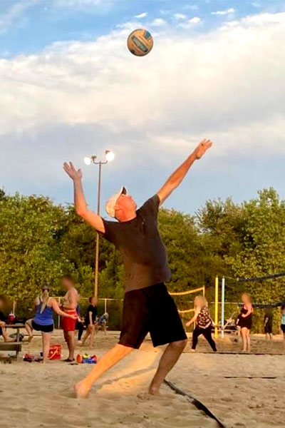 Greg Mosier jumps to spike a volleyball over the net.