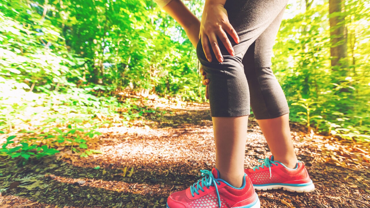 lower half of person on nature trail holding knee