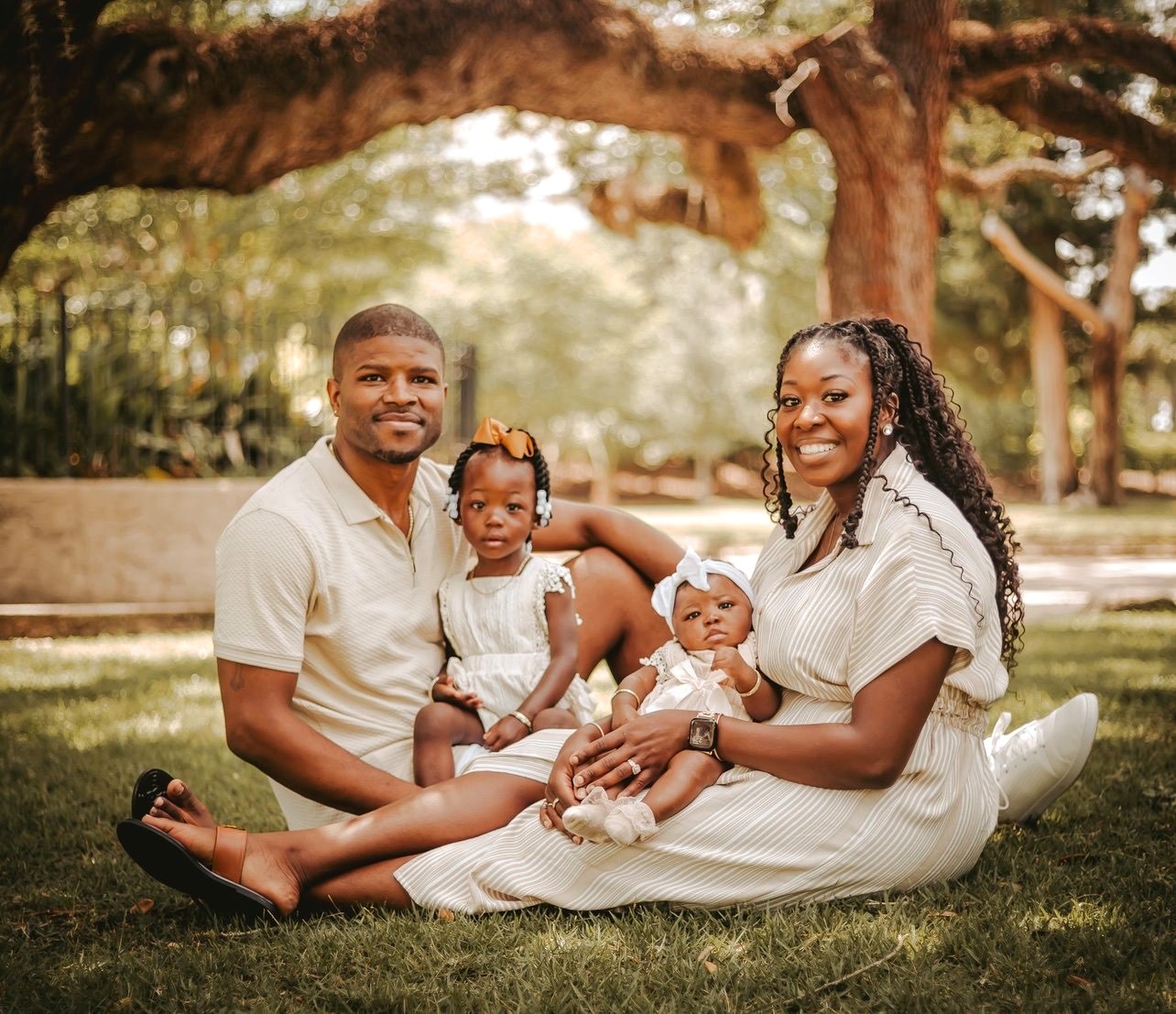 Serina and Larry Bailey with sit under a tree with their children.