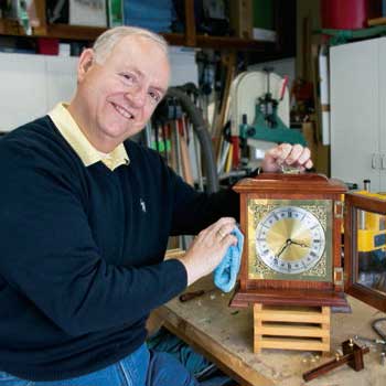 Cancer survivor George Haskin smiles while polishing an antique clock. 