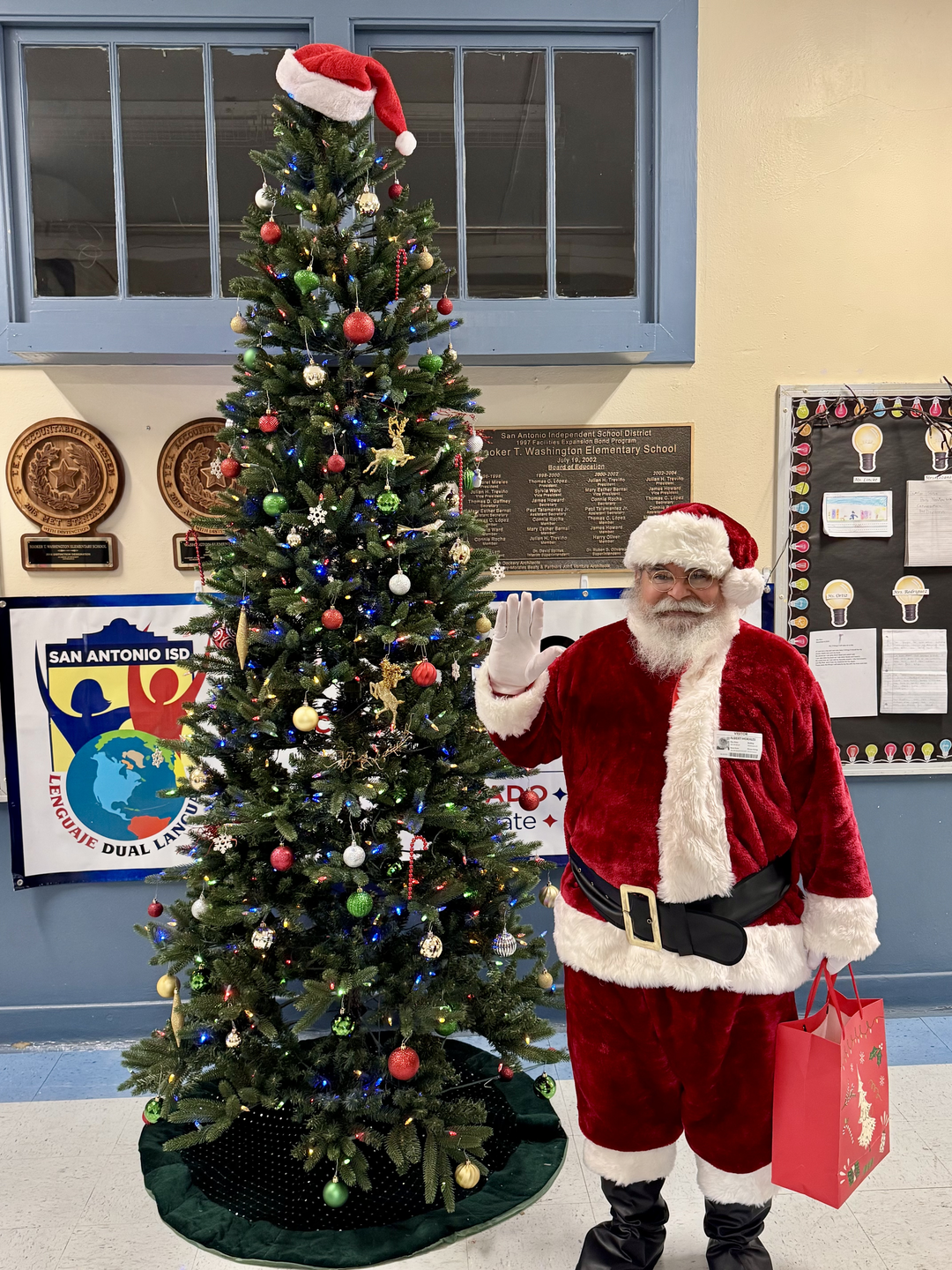 Albert Morales dressed as Santa Claus standing next to a Christmas tree