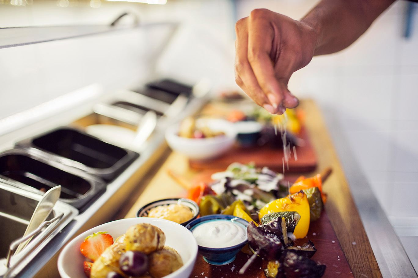 A chef preparing trays of vegetarian shashlik in a restaurant kitchen.
