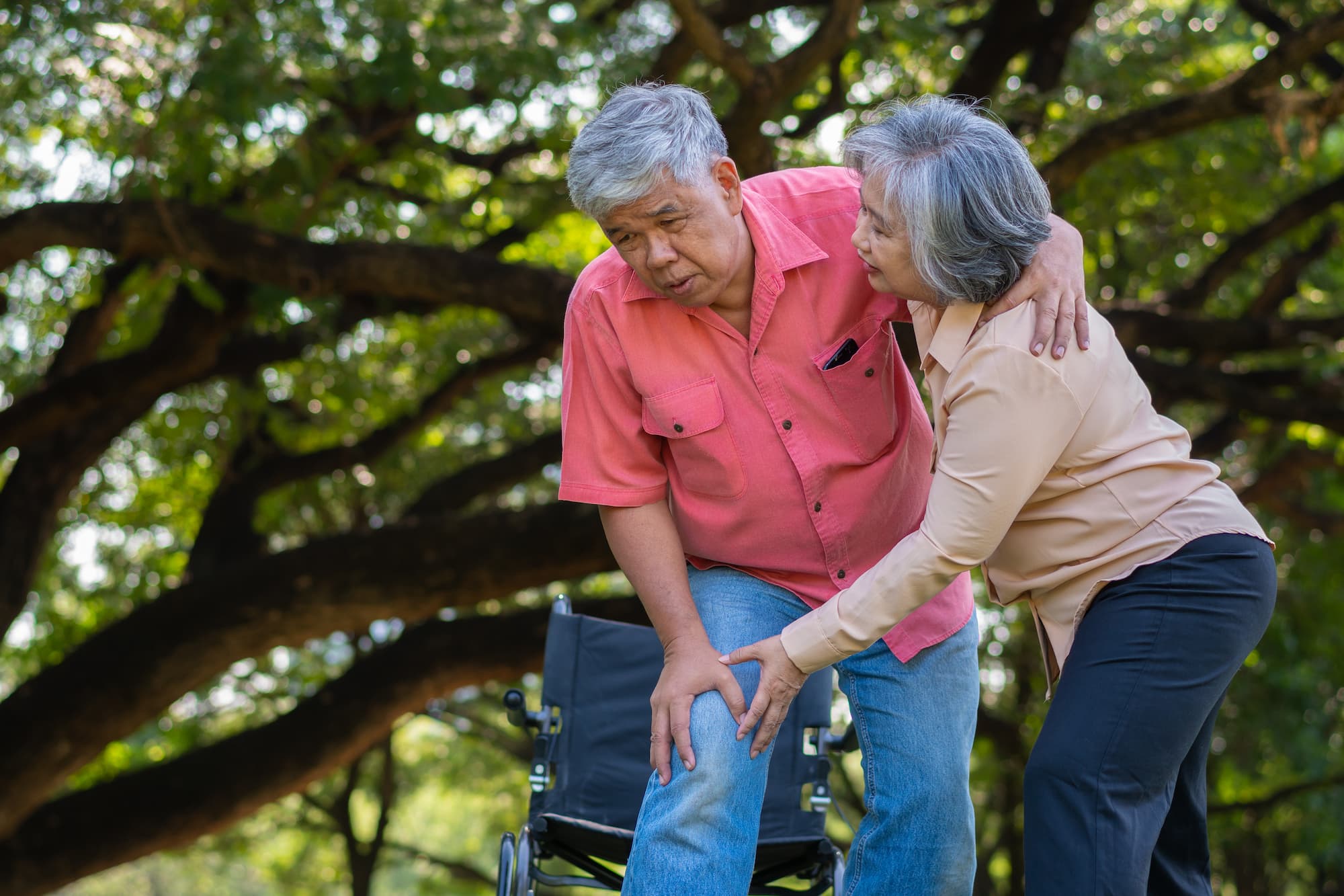 Senior man falling down as his wife works to help support him.