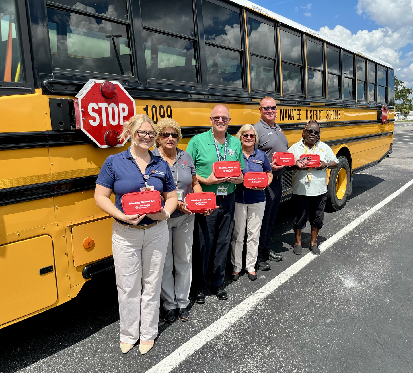 A group of people standing by a school bus holding first aid kits.