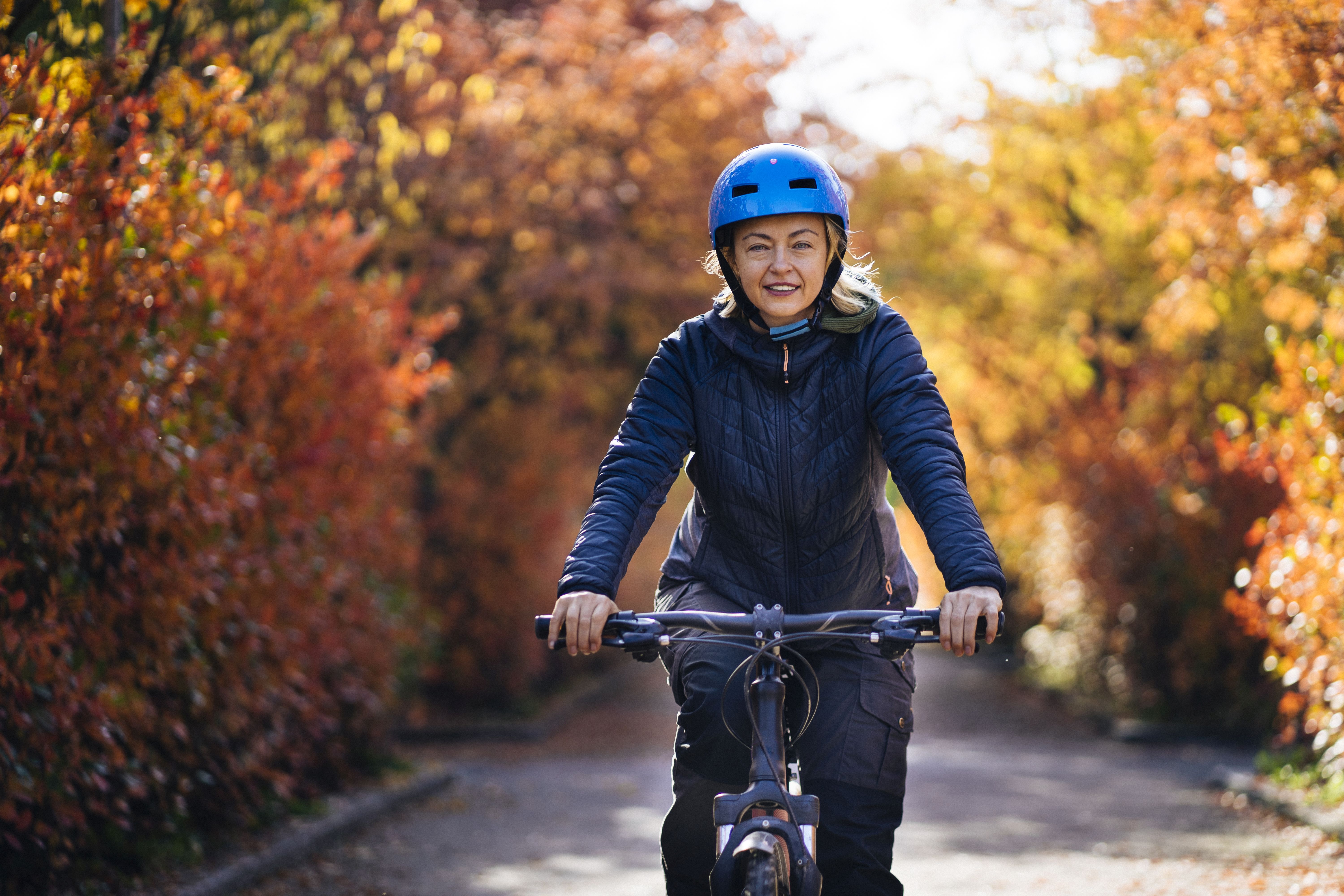 A lady rides her bike on a pretty autumn day