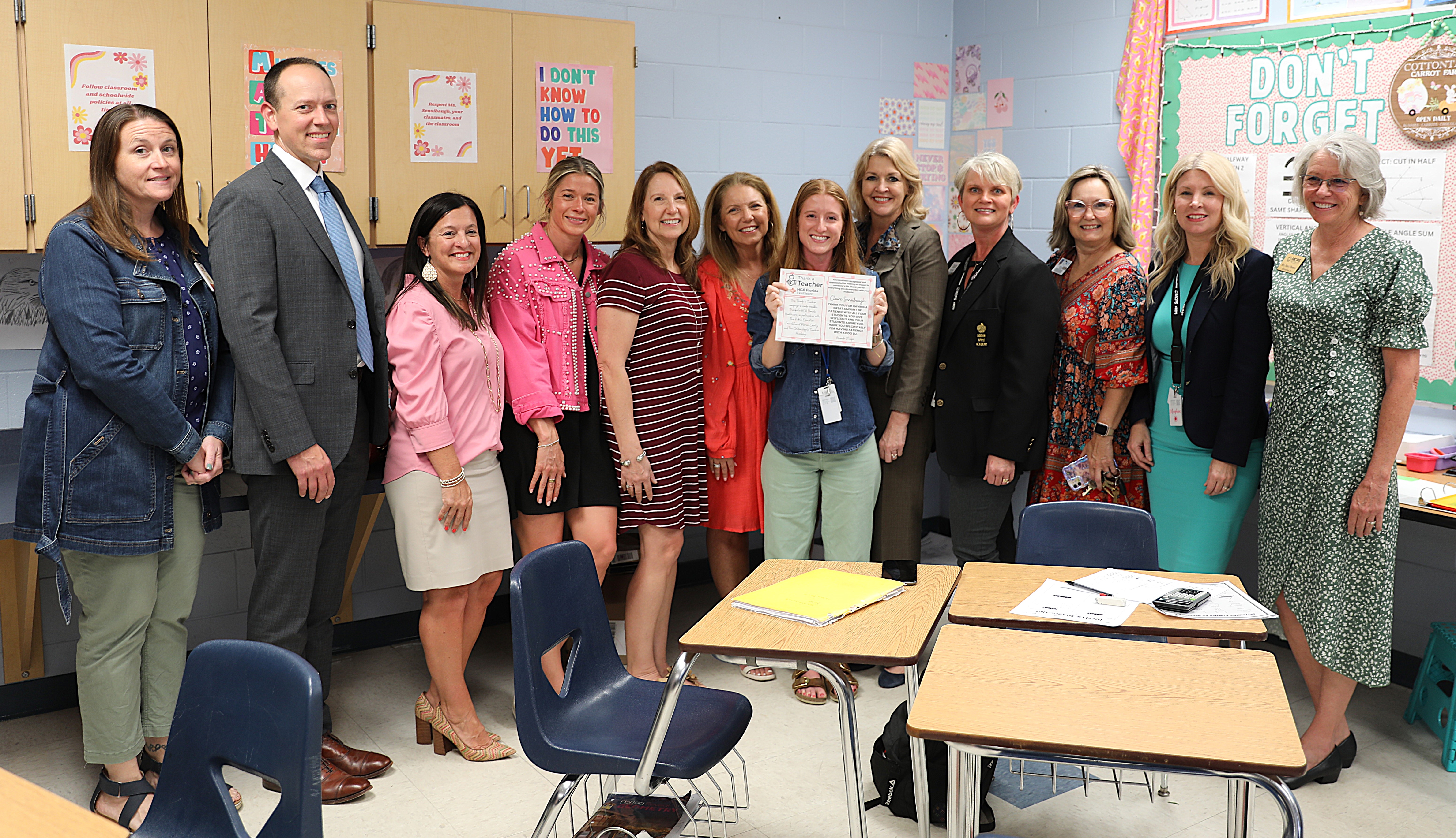 Claire Sensibaugh holding two vases with flowers and Thank a Teacher signage.