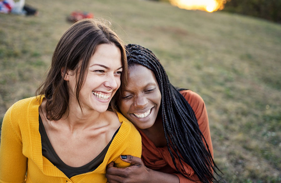 Two women embracing outdoors on a hill