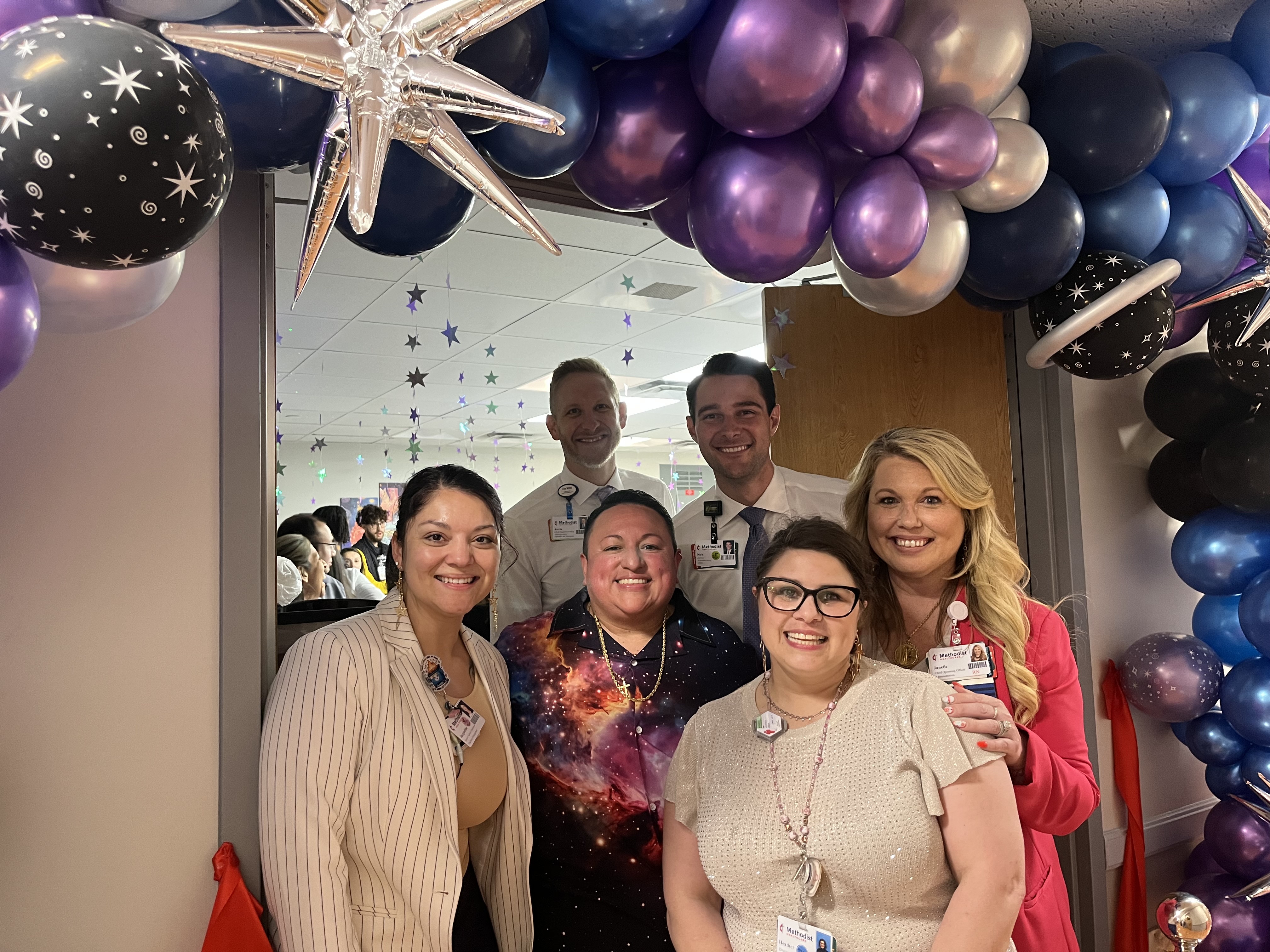 Hospital staff at celebration with ornate purple and blue balloons.