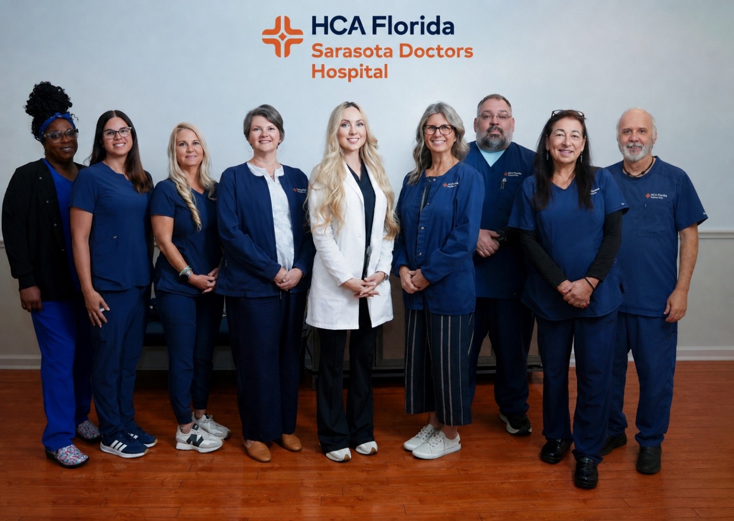 Group of nurses stand smiling under the logo "HCA Florida Sarasota Doctors Hospital".