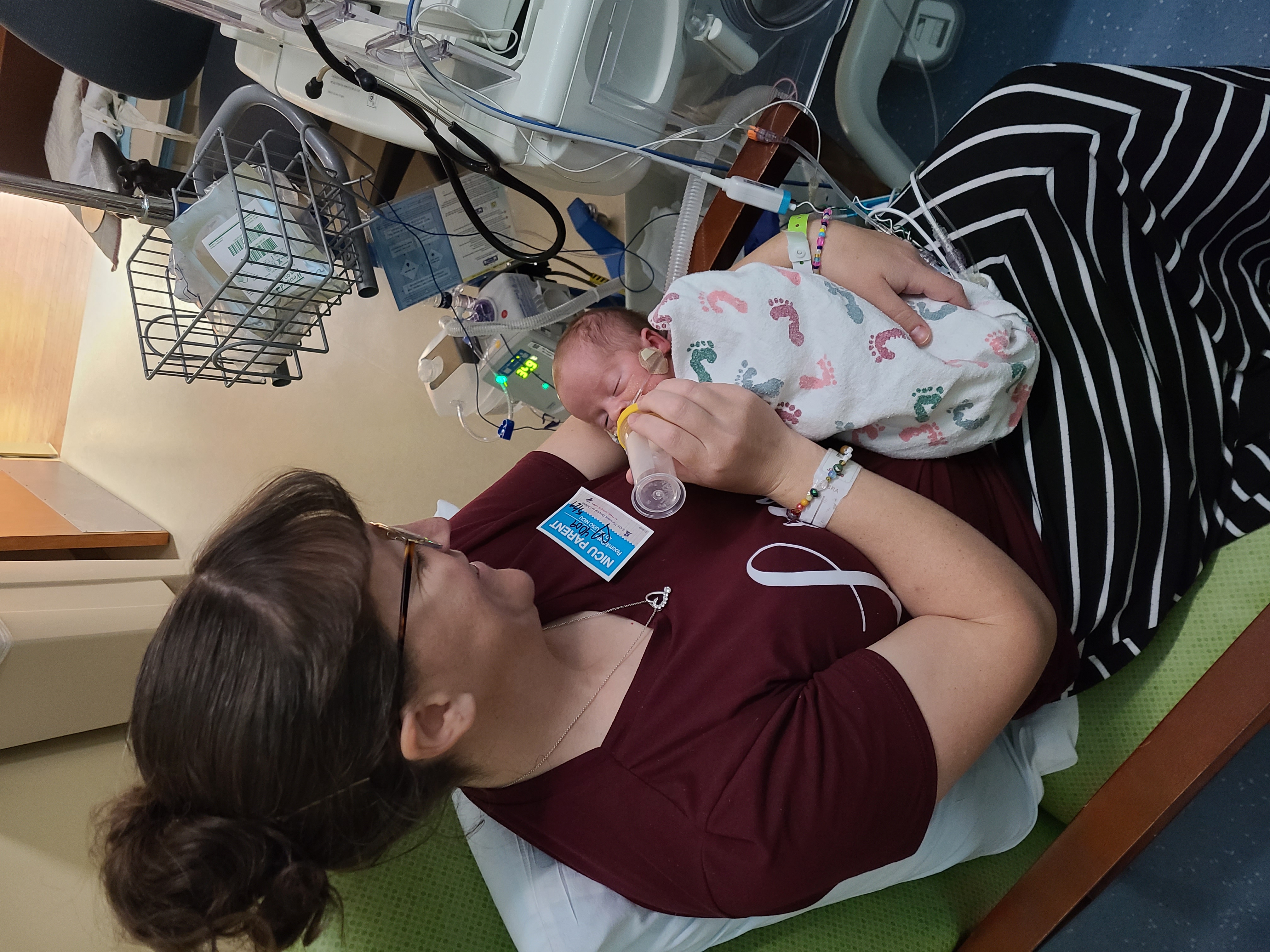 Becca holding tiny Timothy in NICU, feeding bottle