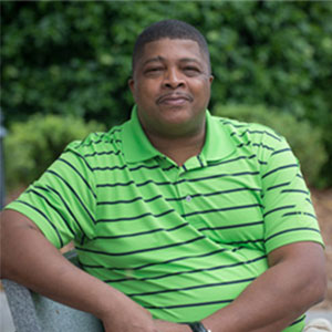 Rufus Austin sitting outside, wearing a green polo shirt with black stripes.