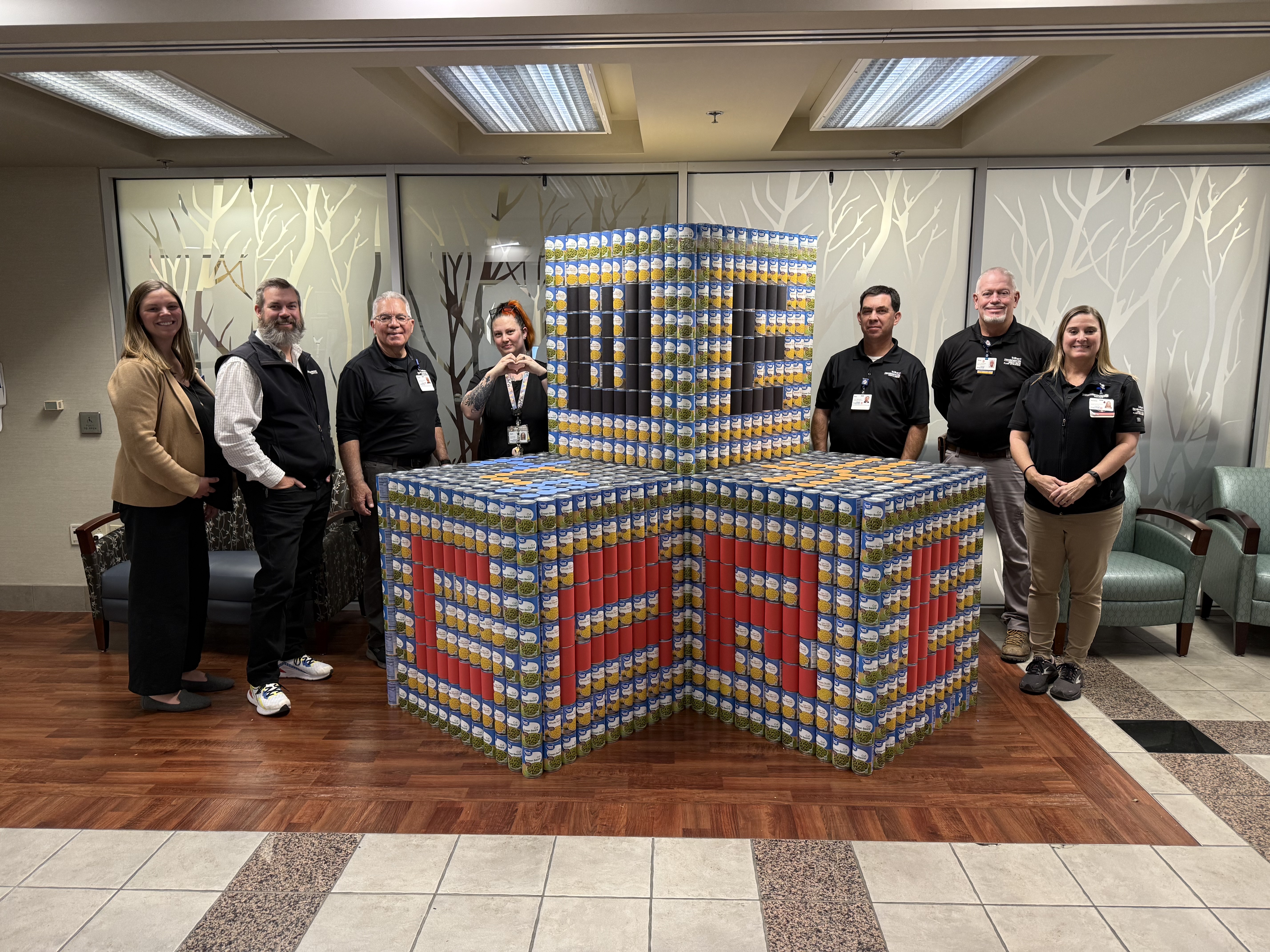 HCA team members next to large blocks of canned foods.