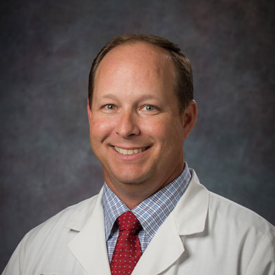 Dr. Oliver C. Whipple, MD, FACS, FASMBS smiling while wearing a physician's jacket.