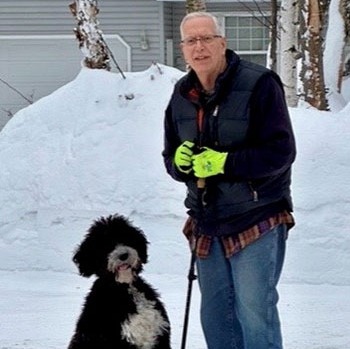 Ross Fosberg standing in the snow with his dog.