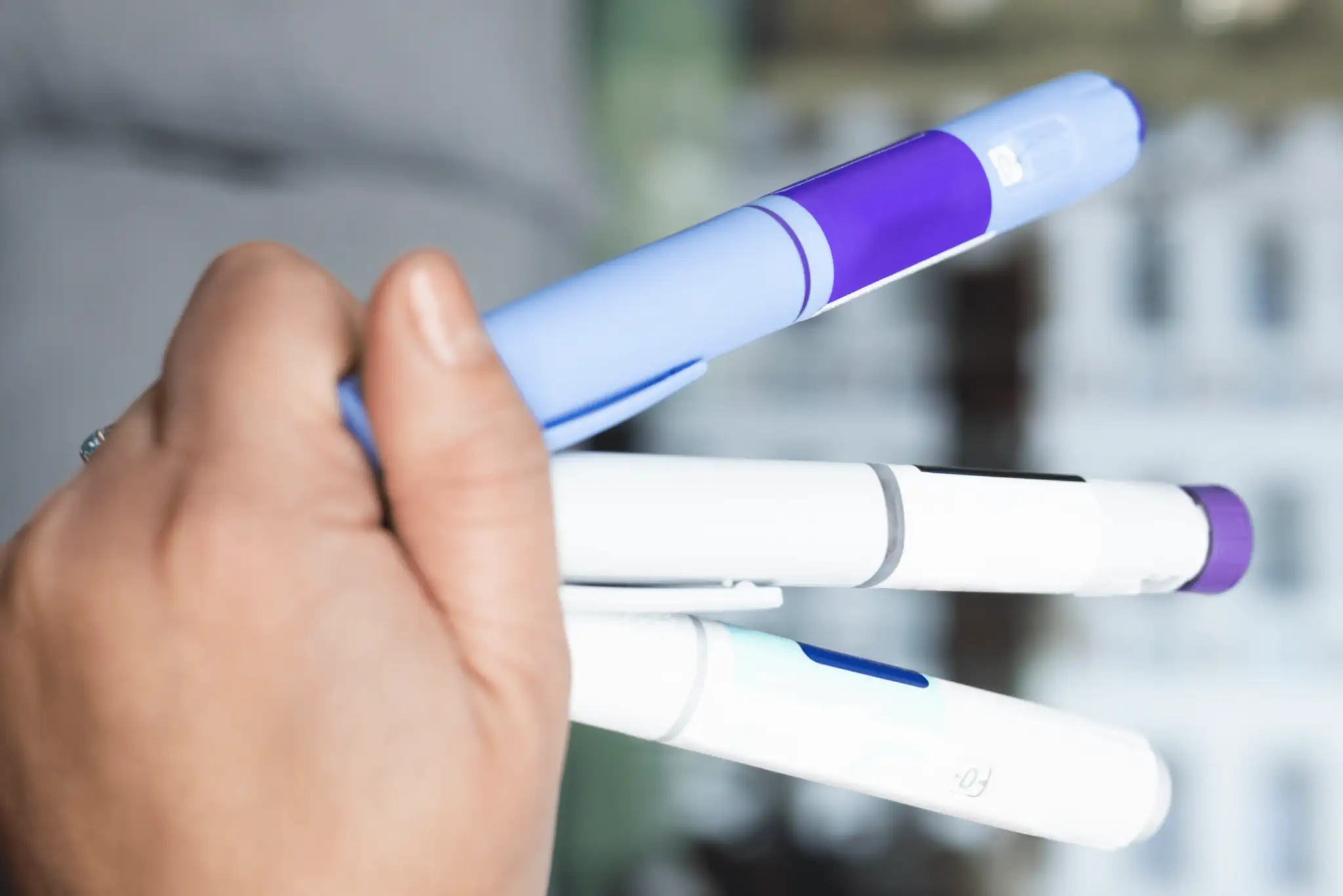 Hand holding three GLP-1 Pens.