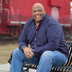 Ernest Ferguson smiles while sitting on a bench in a park.