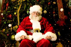 James Currie dressed as Santa sitting in front a Christmas tree