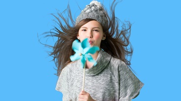 A woman in hat blowing into a pinwheel