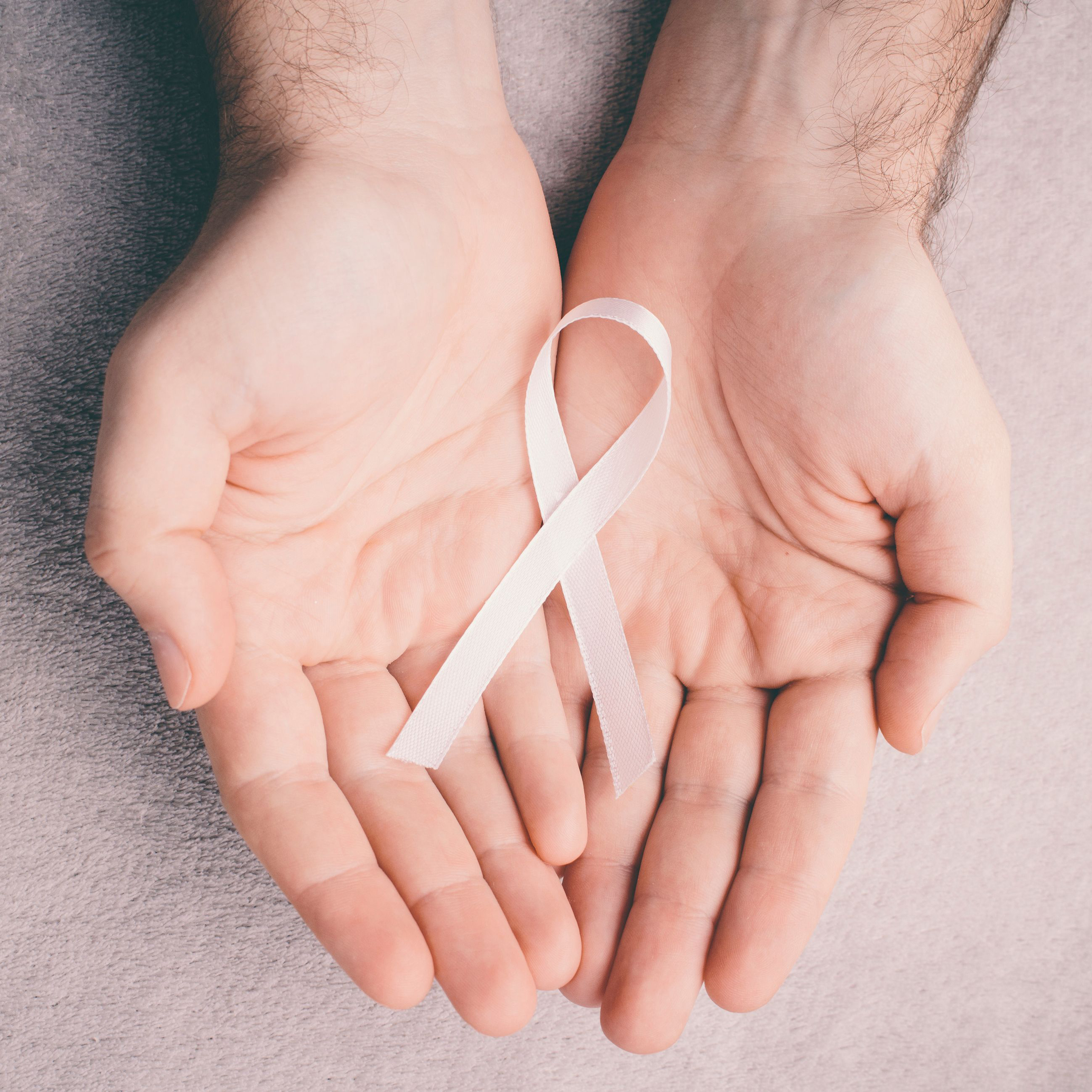 A closeup of two hands holding an awareness ribbon.