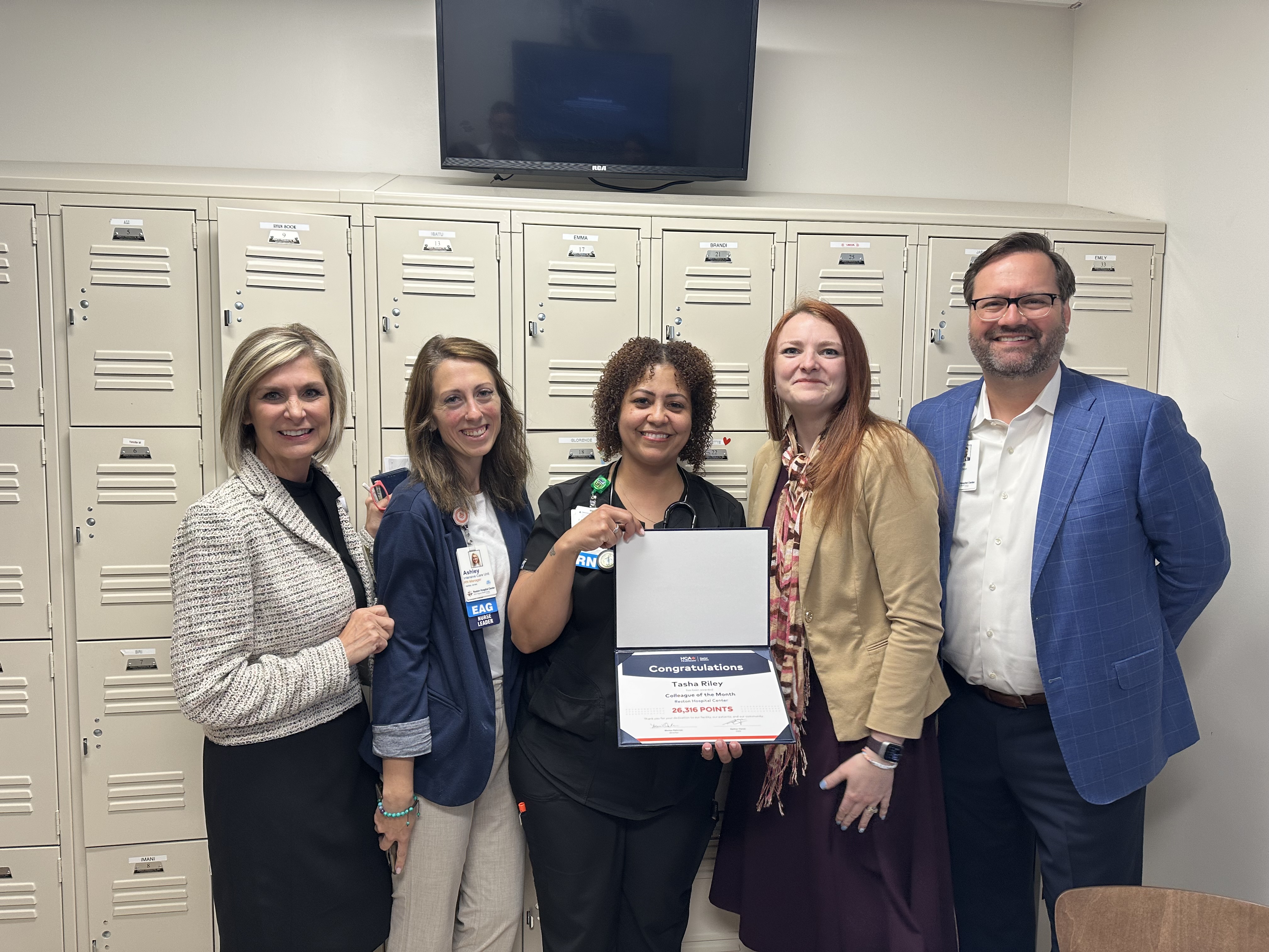 Latasha Riley holding award, acknowledged as the March Colleague of the Month by Reston Hospital leadership for her compassionate care of this IMC patient