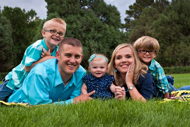 Holly Steinbeck, her husband, and three children, sitting on grass, smiling.