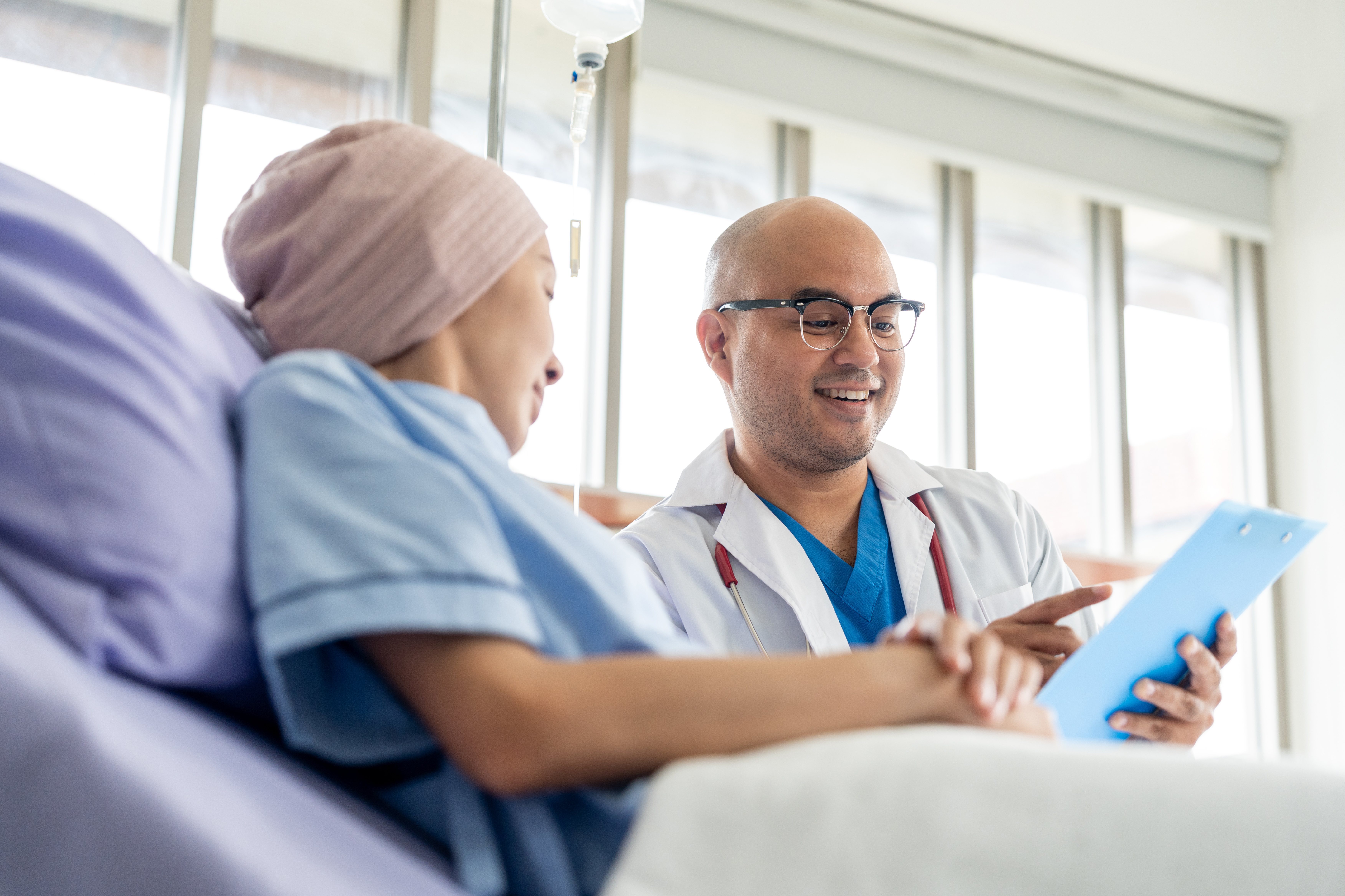 Male doctor visiting female cancer patient with care and compassion in hospital room.